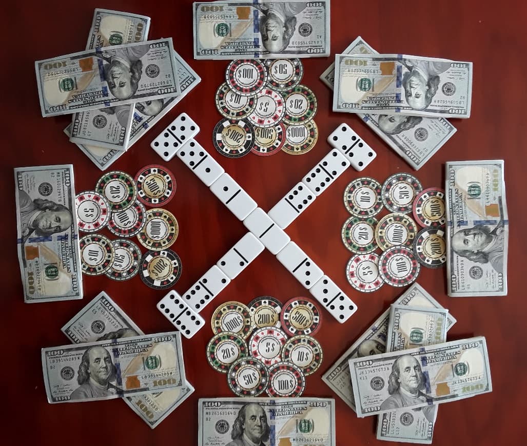 Domino tiles, poker chips and cash laid out on a table